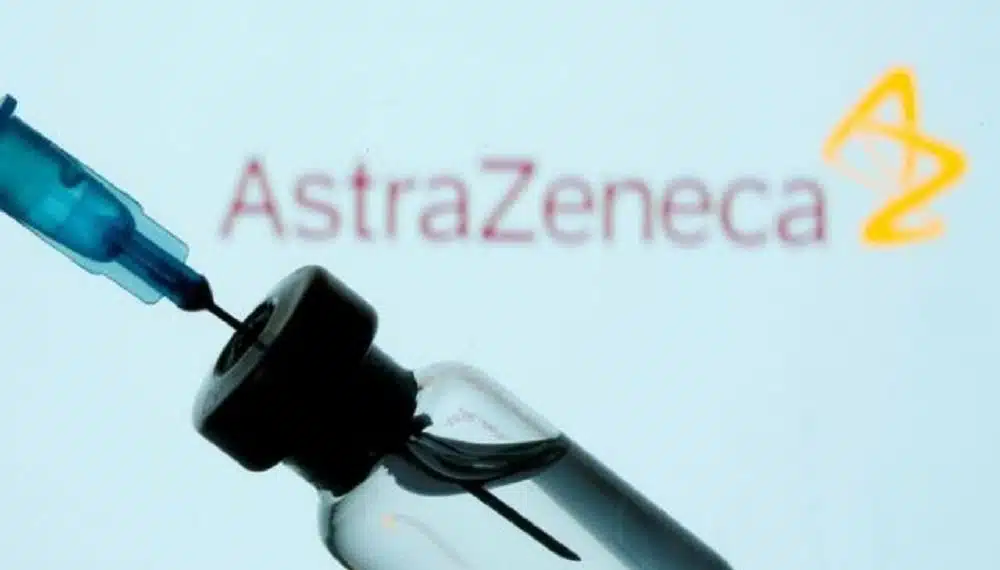COVID-19 Vaccine - A vial and syringe are seen in front of a displayed AstraZeneca logo.