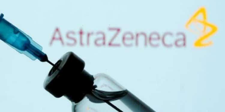 COVID-19 Vaccine - A vial and syringe are seen in front of a displayed AstraZeneca logo.
