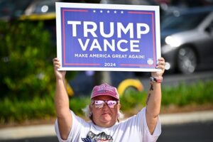 A supporter of former US President and Republican presidential candidate Donald Trump holds a sign on Election Day, in The Villages, Florida, November 5, 2024. (Photo by Miguel J. Rodriguez Carrillo / AFP)