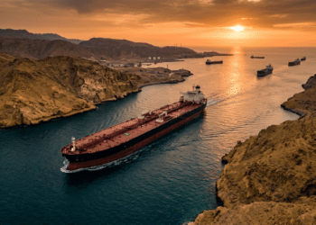 Aerial view of an oil tanker transiting the Strait of Hormuz chokepoint, illustrating the critical global energy shipping route during a dramatic sunset.