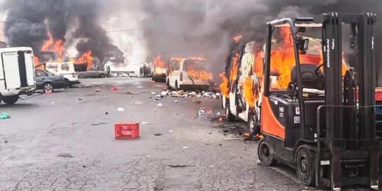 Smoke rises from torched vehicles during Eastern Cape violence over Nigerian king installation.