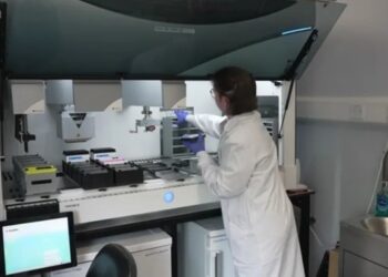 Scientist in Edinburgh laboratory using AI in neurological research to analyze stem-cell-derived brain neurones for motor neurone disease treatment.